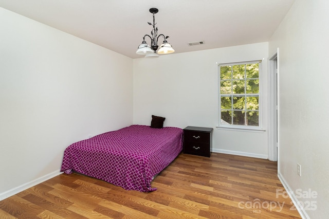 10816 Pointer Ridge Dr, Charlotte, NC 28214 - bedroom with a chandelier, wood finished floors, and baseboards