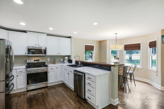 10311 Windtree Ln, Charlotte, NC 28215 - kitchen featuring stainless steel appliances, a sink, a peninsula, a kitchen breakfast bar, and white cabinetry