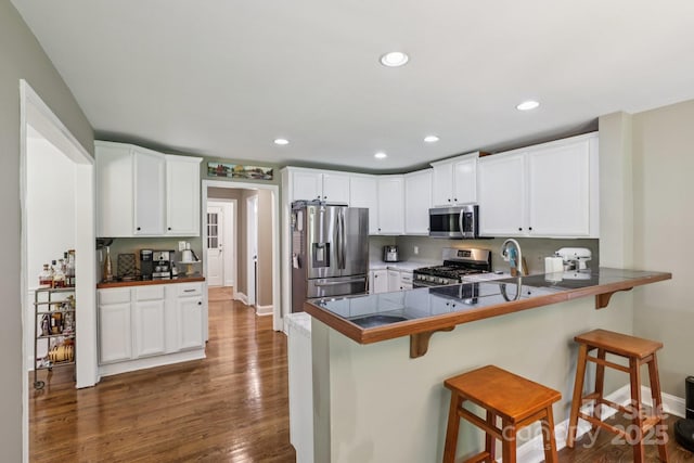10311 Windtree Ln, Charlotte, NC 28215 - kitchen with stainless steel appliances, a kitchen breakfast bar, dark wood-type flooring, a peninsula, and white cabinets