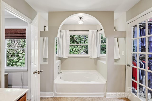 10311 Windtree Ln, Charlotte, NC 28215 - bathroom with a garden tub, vanity, a spacious closet, and baseboards