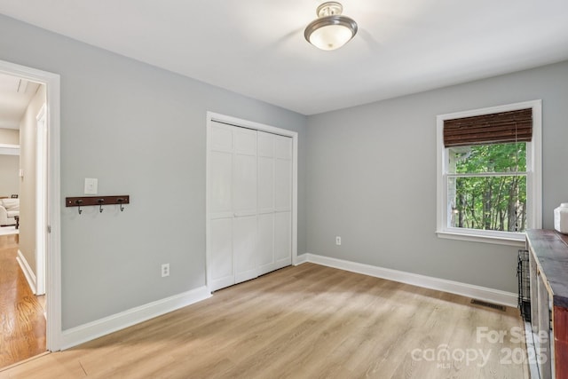 10311 Windtree Ln, Charlotte, NC 28215 - unfurnished bedroom featuring light wood finished floors, a closet, baseboards, and attic access