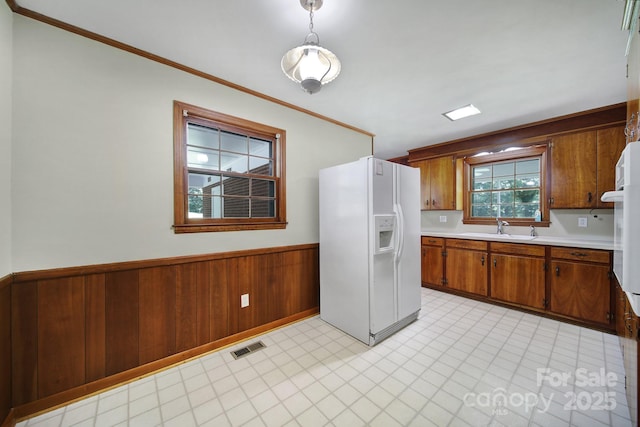 967 Hilldale Dr, Lancaster, SC 29720 - kitchen featuring white fridge with ice dispenser, a sink, brown cabinetry, light countertops, and wainscoting