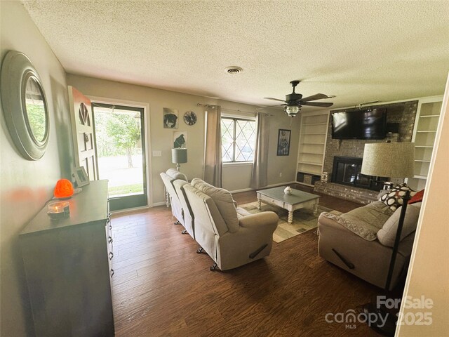 136 Christopher Rd, Marion, NC 28752 - living room featuring wood finished floors, a textured ceiling, a ceiling fan, a fireplace, and built in features