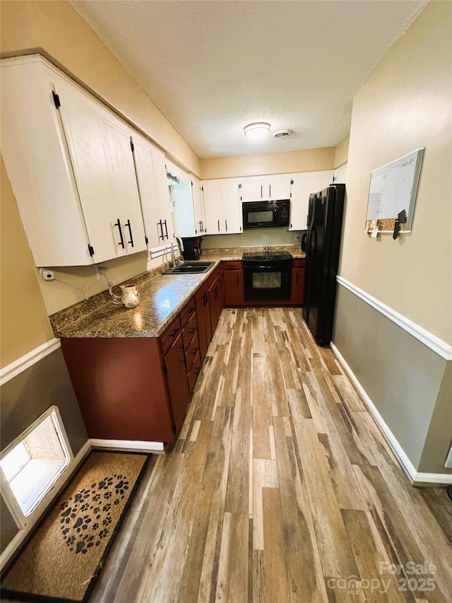 136 Christopher Rd, Marion, NC 28752 - kitchen with black appliances, light wood-type flooring, white cabinets, and a textured ceiling
