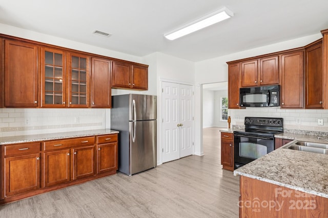 5002 Abode Lily Ln, Charlotte, NC 28227 - kitchen featuring black appliances, light wood finished floors, glass insert cabinets, and decorative backsplash
