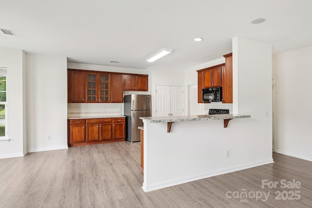 5002 Abode Lily Ln, Charlotte, NC 28227 - kitchen featuring black microwave, freestanding refrigerator, light wood-type flooring, backsplash, and recessed lighting