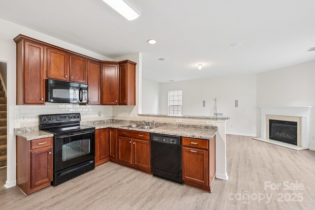 5002 Abode Lily Ln, Charlotte, NC 28227 - kitchen featuring black appliances, light wood-style floors, a peninsula, and recessed lighting
