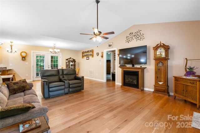 251 Vera Ln, Columbus, NC 28722 - living room featuring a chandelier, a glass covered fireplace, light wood-style floors, lofted ceiling, and ceiling fan