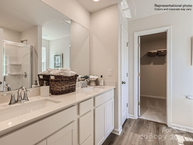 2118 Columbidae Ln, Gastonia, NC 28052 - full bathroom with wood finished floors, a shower stall, double vanity, a walk in closet, and baseboards
