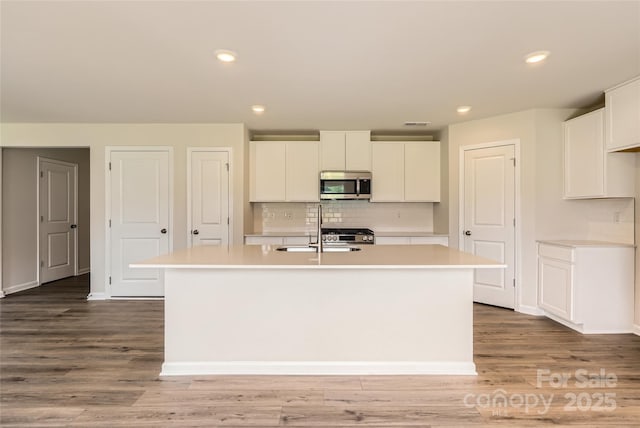 2118 Columbidae Ln, Gastonia, NC 28052 - kitchen featuring stainless steel microwave, light countertops, an island with sink, white cabinets, and recessed lighting