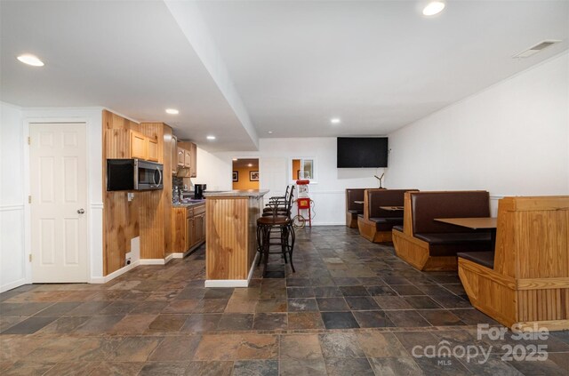4201 Amber Leigh Way Dr, Charlotte, NC 28269 - kitchen with stainless steel microwave, a kitchen island, a breakfast bar, recessed lighting, and dark stone finish flooring