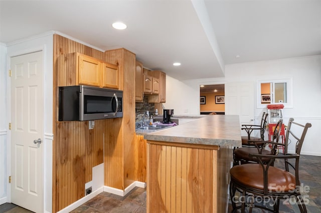 4201 Amber Leigh Way Dr, Charlotte, NC 28269 - kitchen featuring stainless steel microwave, a kitchen bar, light brown cabinets, backsplash, and recessed lighting