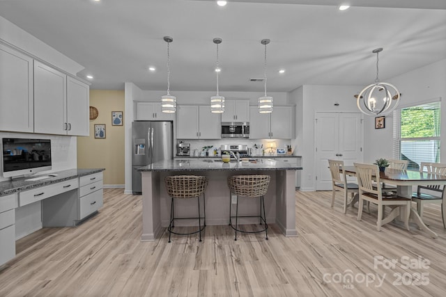 229 Cramerton Mills Parkway, Cramerton, NC 28032 - kitchen with stainless steel appliances, light wood-style flooring, a kitchen bar, a center island with sink, and baseboards