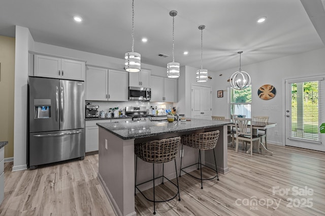 229 Cramerton Mills Parkway, Cramerton, NC 28032 - kitchen with appliances with stainless steel finishes, light wood-type flooring, an island with sink, a breakfast bar, and dark stone counters