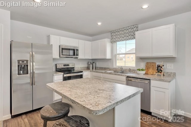 10127 Florentine Way, Charlotte, NC 28214 - kitchen featuring appliances with stainless steel finishes, a sink, wood finished floors, white cabinetry, and a breakfast bar