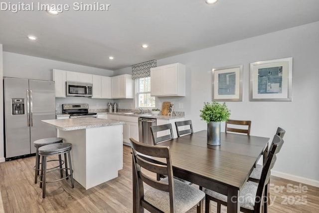 10127 Florentine Way, Charlotte, NC 28214 - kitchen featuring appliances with stainless steel finishes, a kitchen island, white cabinets, light countertops, and a sink