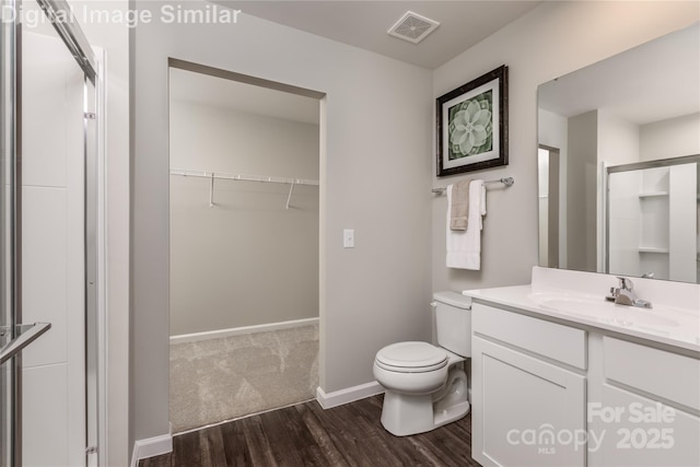 10127 Florentine Way, Charlotte, NC 28214 - bathroom featuring wood finished floors, vanity, toilet, a walk in closet, and a stall shower