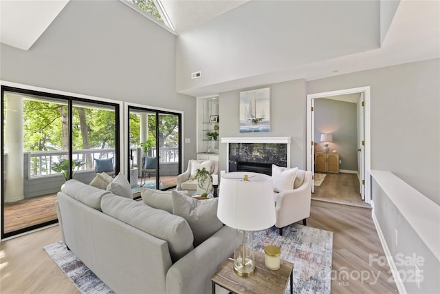 303 NW Dr, Davidson, NC 28036 - living area featuring high vaulted ceiling, light wood finished floors, a premium fireplace, and baseboards