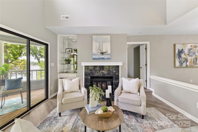 303 NW Dr, Davidson, NC 28036 - living area with wood finished floors, a fireplace, baseboards, and a high ceiling