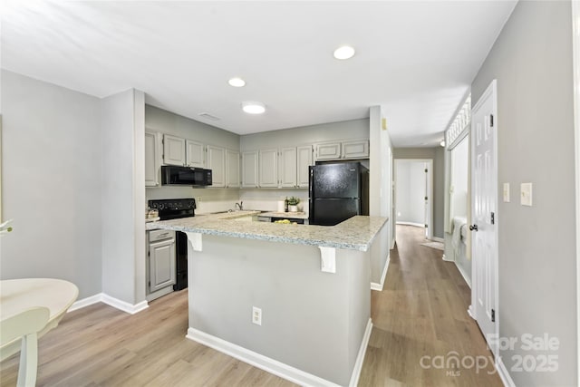 303 NW Dr, Davidson, NC 28036 - kitchen with black appliances, light wood-type flooring, a center island, light stone counters, and baseboards