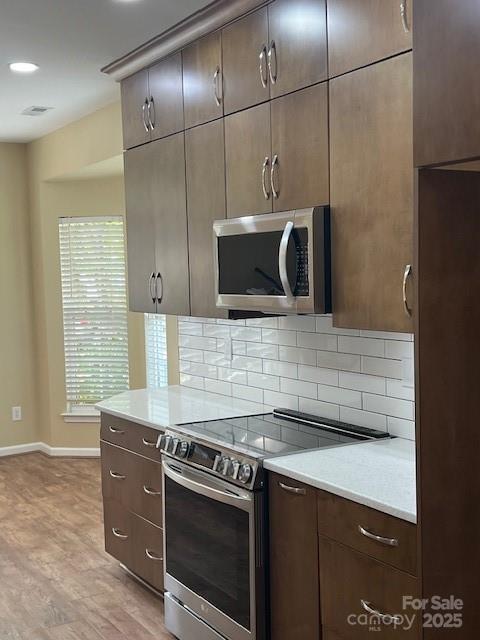 12378 Swan Wings Pl, Huntersville, NC 28078 - kitchen featuring stainless steel appliances, decorative backsplash, baseboards, light countertops, and light wood-style flooring