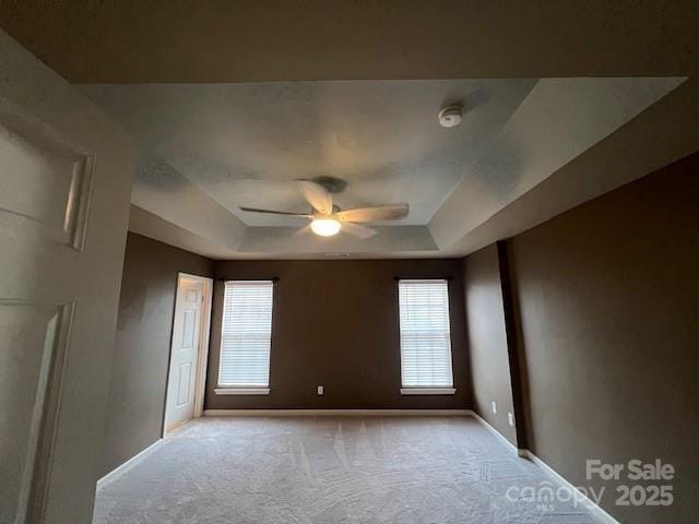 12378 Swan Wings Pl, Huntersville, NC 28078 - carpeted spare room featuring a raised ceiling, ceiling fan, baseboards, and healthy amount of natural light