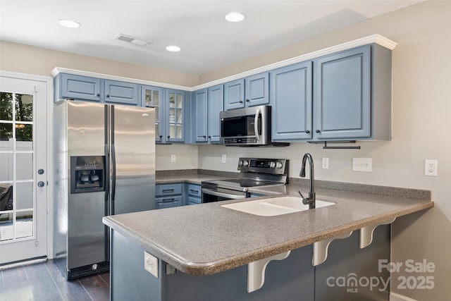 1925 Sandal Brook Rd, Indian Land, SC 29707 - kitchen with appliances with stainless steel finishes, a peninsula, blue cabinets, glass insert cabinets, and a kitchen bar