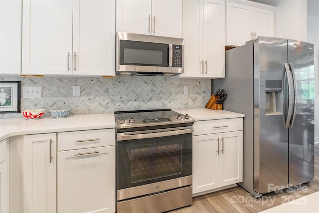 819 Anderson St, Charlotte, NC 28205 - kitchen with appliances with stainless steel finishes, white cabinetry, light countertops, light wood finished floors, and decorative backsplash