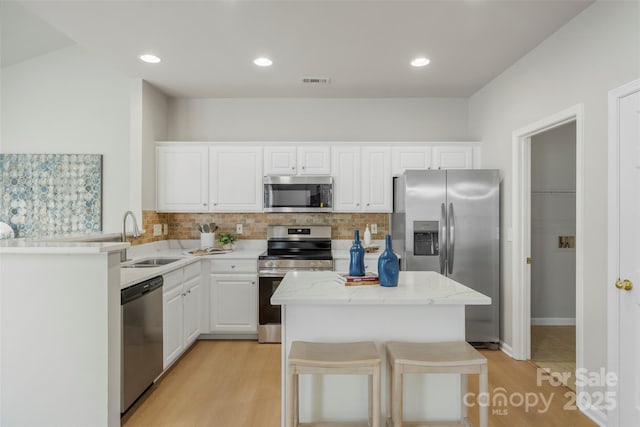 10225 Alexander Martin Ave, Charlotte, NC 28277 - kitchen featuring stainless steel appliances, tasteful backsplash, light wood-type flooring, white cabinetry, and light stone counters