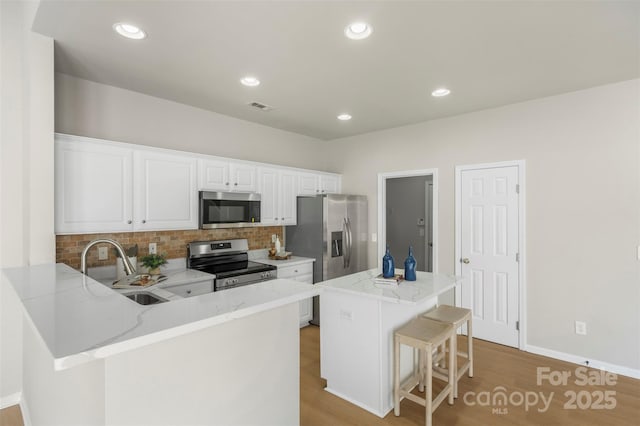10225 Alexander Martin Ave, Charlotte, NC 28277 - kitchen featuring appliances with stainless steel finishes, wood finished floors, a breakfast bar area, backsplash, and recessed lighting