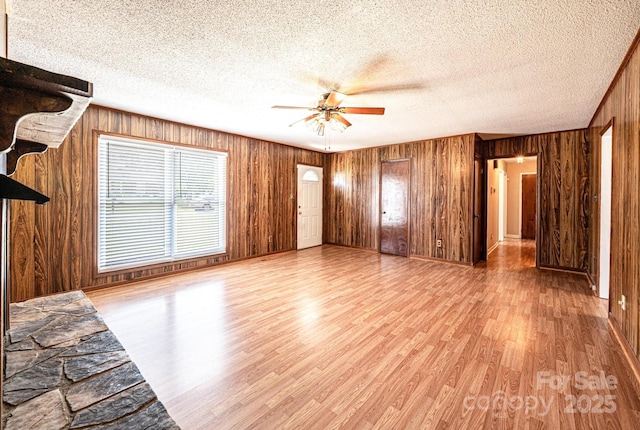 2031 36th St NE, Hickory, NC 28601 - unfurnished living room with wooden walls, wood finished floors, a ceiling fan, and a textured ceiling