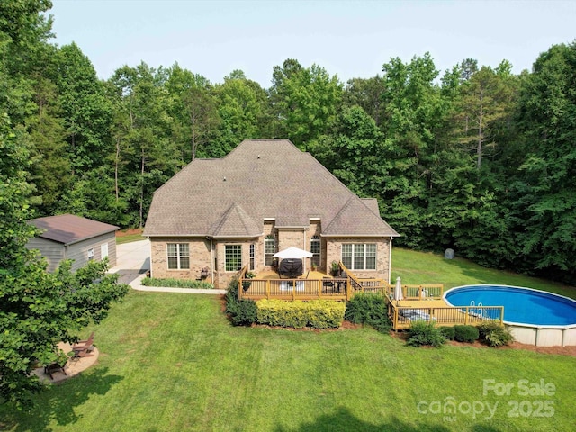 8101 Cane Pointe Ln, Waxhaw, NC 28173 - back of house with a wooden deck, an outdoor pool, brick siding, a yard, and a view of trees