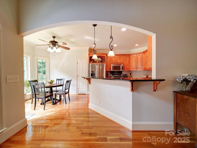 8101 Cane Pointe Ln, Waxhaw, NC 28173 - kitchen with appliances with stainless steel finishes, arched walkways, a kitchen bar, dark countertops, and crown molding