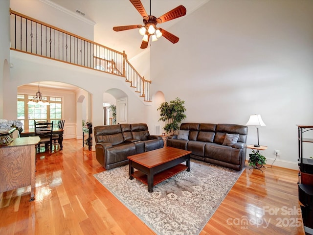8101 Cane Pointe Ln, Waxhaw, NC 28173 - living room featuring arched walkways, light wood finished floors, ceiling fan, a towering ceiling, and a chandelier