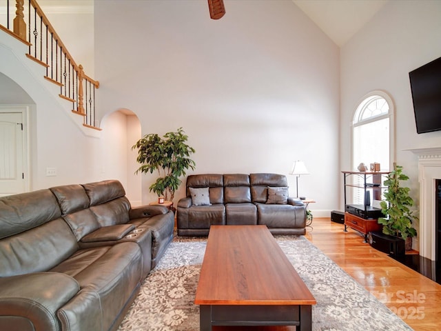 8101 Cane Pointe Ln, Waxhaw, NC 28173 - living room featuring high vaulted ceiling, arched walkways, wood finished floors, a fireplace, and stairs