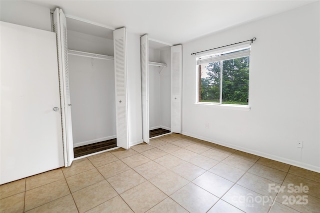 326 Orchard Trace Ln Unit 3, Charlotte, NC 28213 - unfurnished bedroom with light tile patterned flooring, baseboards, and two closets