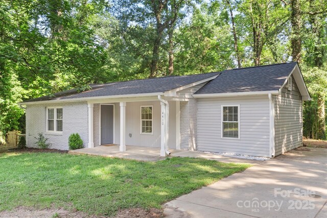 4410 Burgin St, Kannapolis, NC 28081 - ranch-style home featuring a front lawn, a shingled roof, and view of wooded area