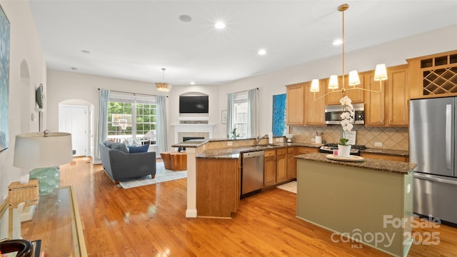 4115 Birkshire Hts, Fort Mill, SC 29708 - kitchen with appliances with stainless steel finishes, a peninsula, open floor plan, backsplash, and light wood-style floors