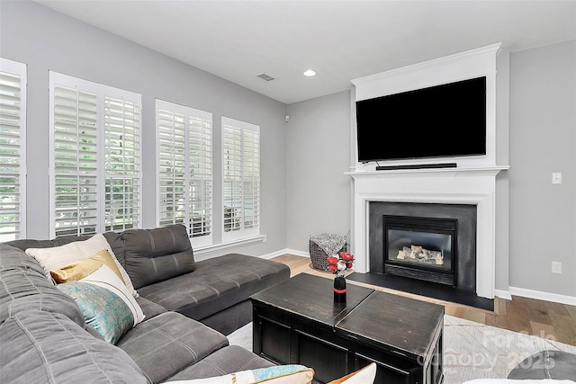 8722 Heron Glen Dr, Charlotte, NC 28269 - living area featuring wood finished floors, baseboards, a fireplace with flush hearth, and recessed lighting
