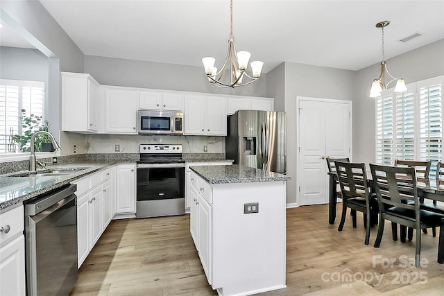 8722 Heron Glen Dr, Charlotte, NC 28269 - kitchen with stainless steel appliances, a sink, light wood-type flooring, and a center island