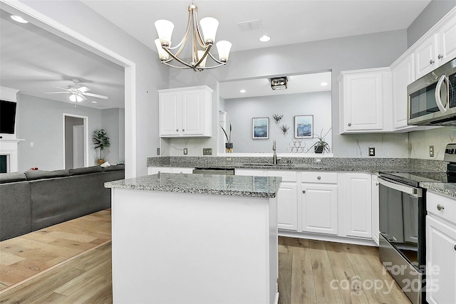 8722 Heron Glen Dr, Charlotte, NC 28269 - kitchen featuring stainless steel appliances, a sink, open floor plan, white cabinets, and recessed lighting
