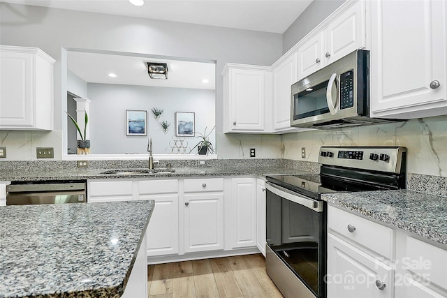 8722 Heron Glen Dr, Charlotte, NC 28269 - kitchen featuring stainless steel appliances, a sink, white cabinetry, light wood-style floors, and tasteful backsplash