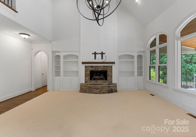 1108 Shinnecock Ln, Waxhaw, NC 28173 - unfurnished living room with high vaulted ceiling, built in features, a chandelier, and a stone fireplace