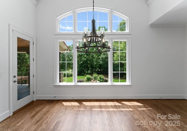 1108 Shinnecock Ln, Waxhaw, NC 28173 - unfurnished dining area with a chandelier, healthy amount of natural light, wood finished floors, crown molding, and a high ceiling