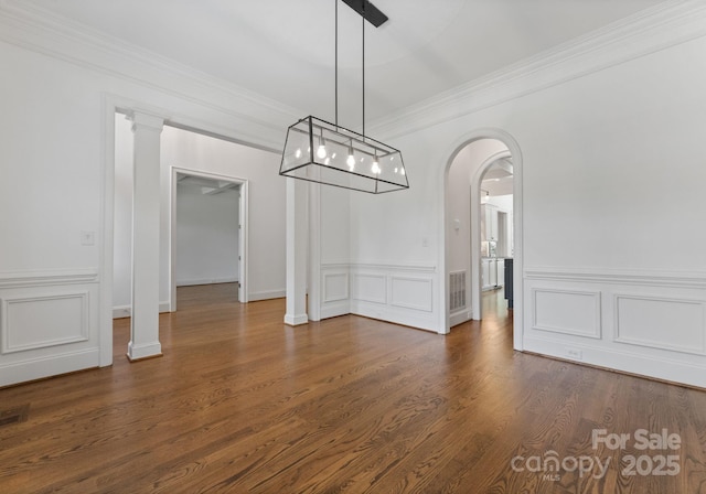 1108 Shinnecock Ln, Waxhaw, NC 28173 - unfurnished dining area featuring ornamental molding, arched walkways, wainscoting, a decorative wall, and dark wood-style floors