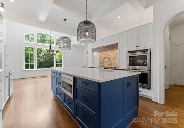 1108 Shinnecock Ln, Waxhaw, NC 28173 - kitchen with appliances with stainless steel finishes, coffered ceiling, blue cabinets, wood finished floors, and arched walkways