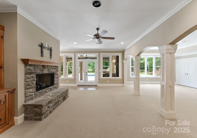 1108 Shinnecock Ln, Waxhaw, NC 28173 - unfurnished living room featuring decorative columns, ceiling fan, ornamental molding, light carpet, and a stone fireplace