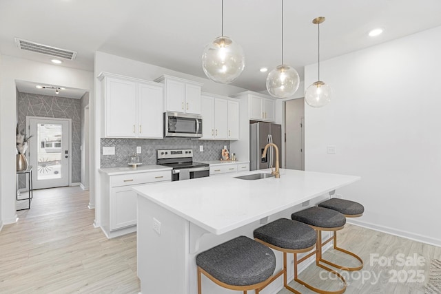 492 Switch St Unit 82Ty, York, SC 29745 - kitchen with appliances with stainless steel finishes, a sink, light wood-style floors, a kitchen island with sink, and white cabinetry