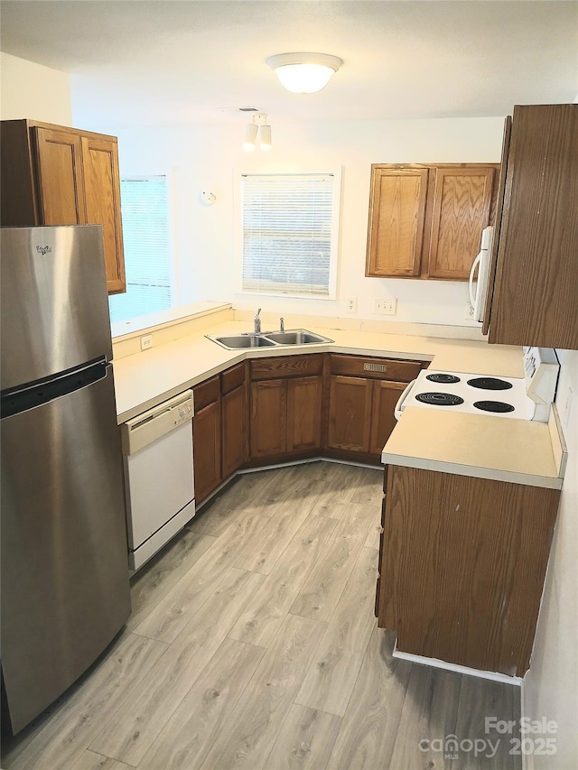 1911 Flushing Ct, Charlotte, NC 28215 - kitchen featuring white appliances, a sink, light wood-type flooring, and brown cabinetry