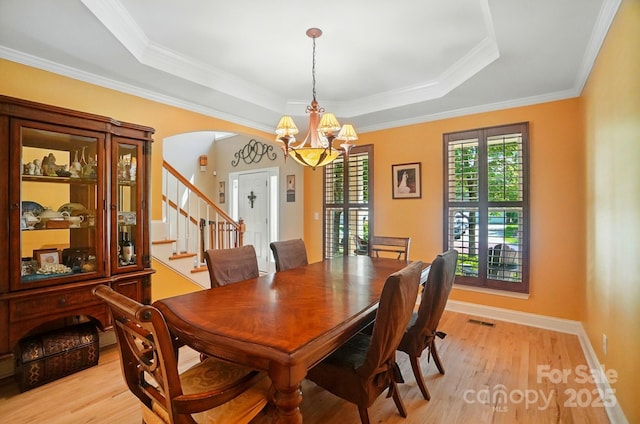 129 N Audubon Ave, Mooresville, NC 28117 - dining room featuring a chandelier, a tray ceiling, light wood-style flooring, arched walkways, and crown molding